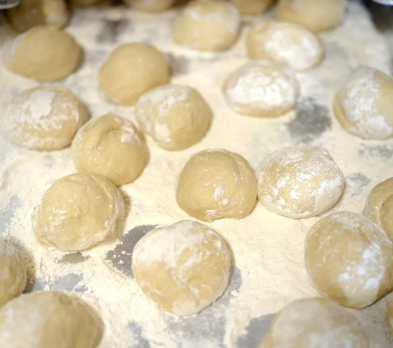 Bolas de masa reposando en una charola enharinada